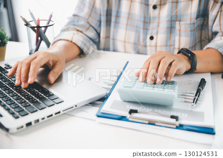 Accountant working on desk using calculator for calculate finance report in office. business finance, calculate tax by organizing financial documents, tracking income investment, accounting by hand. Accountant working on desk using calculator for calculate finance report in office. business finance, calculate tax by organizing financial documents, tracking income investment, accounting by hand. 130124531