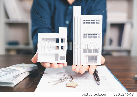 Model house, stacks of coins, calculator, financial documents on a wooden desk represent real estate investment and mortgage planning, highlighting financial growth and strategic planning strategies. Model house, stacks of coins, calculator, financial documents on a wooden desk represent real estate investment and mortgage planning, highlighting financial growth and strategic planning strategies. 130124548