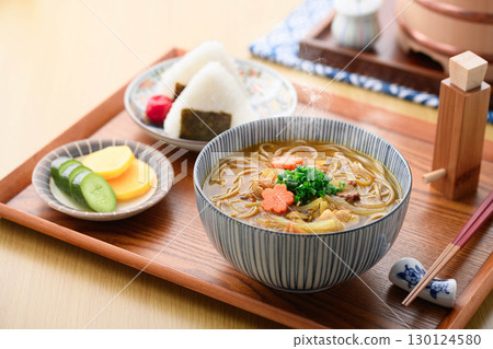 Japanese food scene of hot curry soba and rice ball set meal. Image of steaming noodle dish and pickles on the table. 130124580
