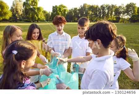 Group of a young volunteers children standing with garbage bags collecting trash in summer park. 130124656
