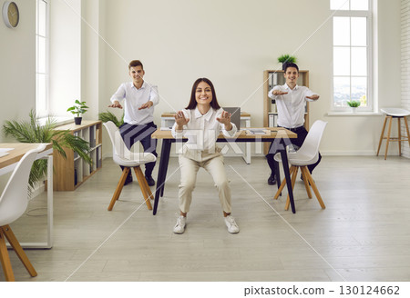 Happy young company employees doing sit-ups exercises in office on their workplace. Happy young company employees doing sit-ups exercises in office on their workplace. 130124662