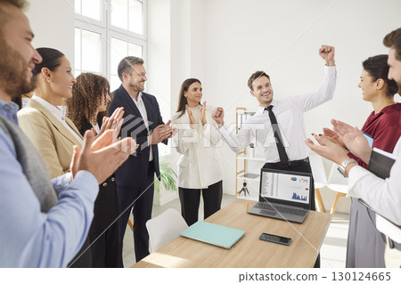 Happy business team celebrating success in work with manager raising fists and colleagues applauding Happy business team celebrating success in work with manager raising fists and colleagues applauding 130124665