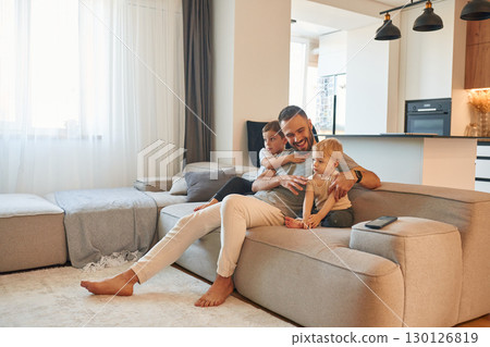 Smiling, positive facial expression. Father with two baby boys is sitting at sofa 130126819