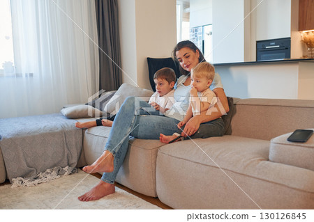 Woman with two little sons is at home on the sofa Woman with two little sons is at home on the sofa 130126845