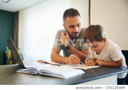 Doing homework. Father and son are at home by the table 130126904