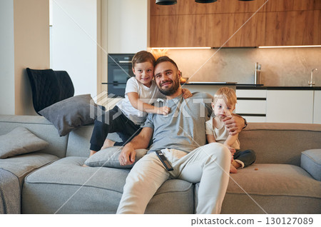 Father with two baby boys is sitting at sofa Father with two baby boys is sitting at sofa 130127089