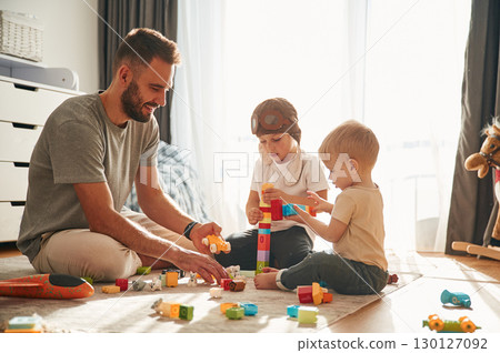 Construction toys. Father is playing with two little boys on the floor Construction toys. Father is playing with two little boys on the floor 130127092