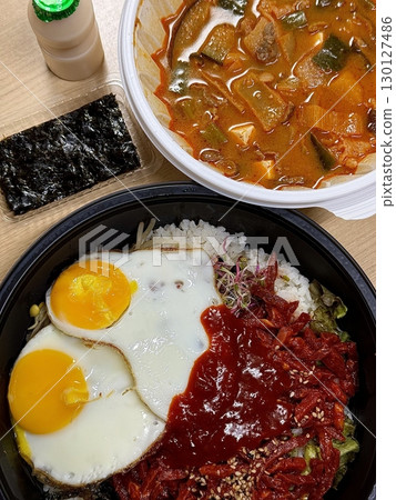 Yukhoe bibimbap with fresh veggies, rice, seasoned raw beef, raw egg yolk, and gochujang offering a bold mix of flavors and textures in a classic Korean dish. Yukhoe bibimbap with fresh veggies, rice, seasoned raw beef, raw egg yolk, and gochujang offering a bold mix of flavors and textures in a classic Korean dish. 130127486