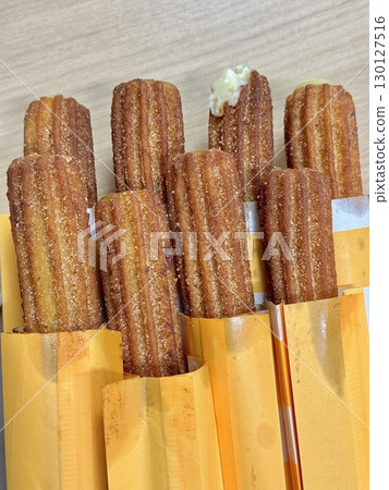 Churros, crispy and golden, dusted with sugar and cinnamon. A delicious, sweet treat often enjoyed with chocolate dipping sauce, perfect for satisfying any dessert craving. 130127516