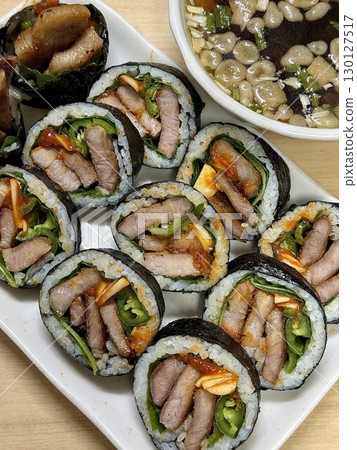 Delicious kimbap rolls filled with fresh vegetables, seasoned rice, and savory proteins, all wrapped in crisp seaweed. A perfect combination of flavor and texture in every bite. 130127517