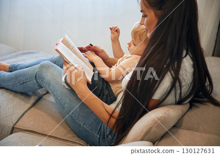 On the legs of woman. Mother with her little son is at home in domestic room On the legs of woman. Mother with her little son is at home in domestic room 130127631
