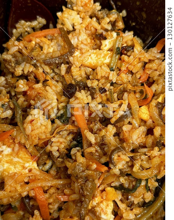 Bibimbap, a vibrant Korean rice dish topped with a variety of seasoned vegetables, gochujang, and a fried egg, often accompanied by sliced meat. Mixed together, it creates a flavorful and balanced. 130127634