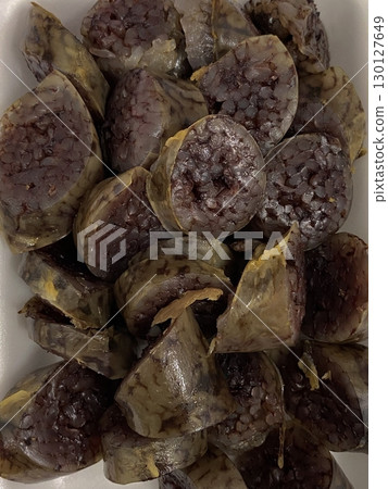 A plate of Korean soondae, traditional blood sausage made with a savory mix of noodles and spices, sliced into bite-sized pieces. Served with dipping salt and chili sauce for extra flavor. 130127649