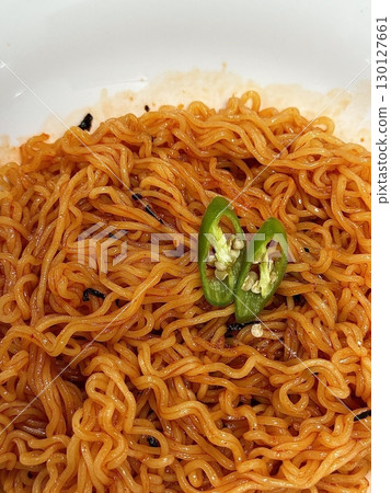 Spicy and tangy bibim guksu with chewy noodles, fresh veggies, and gochujang sauce. A vibrant and refreshing Korean cold noodle dish perfect for a light yet flavorful meal. 130127661