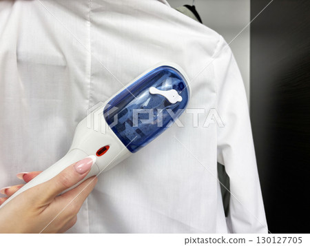 Woman ironing clothes with steam iron at wardrobe. Clothes care and garment steaming. Fashion, laundry, household chores, wrinkle removal. Business and casual clothing care Woman ironing clothes with steam iron at wardrobe. Clothes care and garment steaming. Fashion, laundry, household chores, wrinkle removal. Business and casual clothing care 130127705