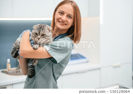 After the check up, holding and smiling. Scottish fold cat in the veterinarian clinic with female doctor After the check up, holding and smiling. Scottish fold cat in the veterinarian clinic with female doctor 130128064