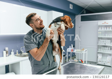 Playful mood, having fun. Dog in veterinarian clinic with male doctor Playful mood, having fun. Dog in veterinarian clinic with male doctor 130128117