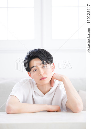 A man looking at the camera with a thoughtful expression, resting his chin on his hands 130128447