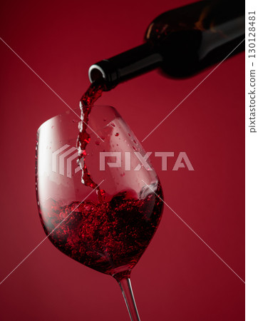 Pouring red wine from a bottle into a glass. Pouring red wine from a bottle into a glass. 130128481