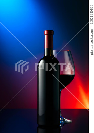 Glass and bottle of red wine on a black reflective background. 130128493