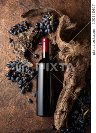 Bottle of red wine with blue grapes and old weathered snags. 130128497
