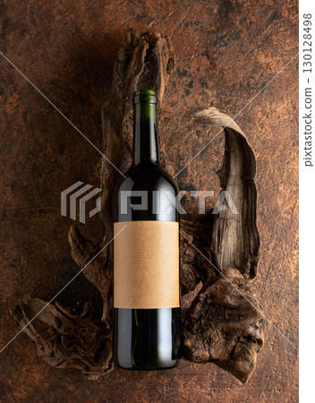 Bottle of red wine and old weathered snags on a brown vintage background. 130128498