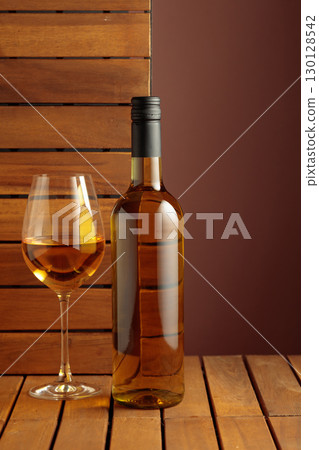 Bottle and glass of white wine on a wooden background. 130128542