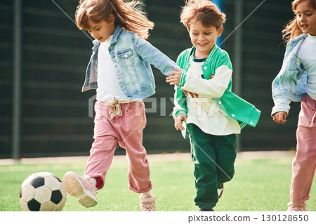 Active weekend. Kids are having fun on the green soccer field together Active weekend. Kids are having fun on the green soccer field together 130128650