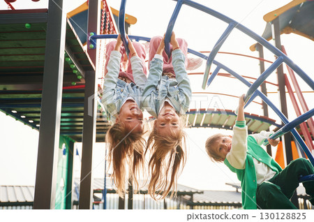 Hanging upside down. Kids are having fun on the playground 130128825