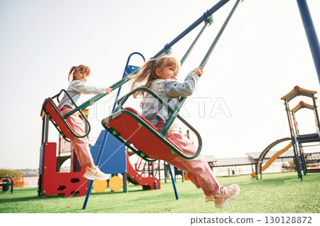 Enjoying swing ride. Kids are having fun on the playground 130128872