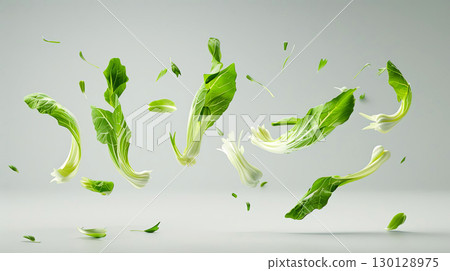 Fresh green vegetables, including leafy greens and herbs, are suspended in mid-air against a soft gray background, showcasing vibrant colors and dynamic movement in a creative culinary concept 130128975