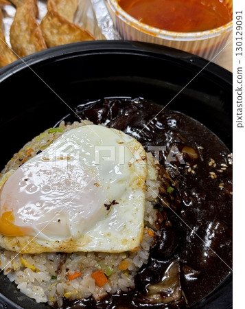 A bowl of jajangmyeon featuring chewy noodles coated in rich black bean sauce, topped with diced pork and vegetables. This iconic Korean-Chinese dish offers a savory and hearty flavor. 130129091