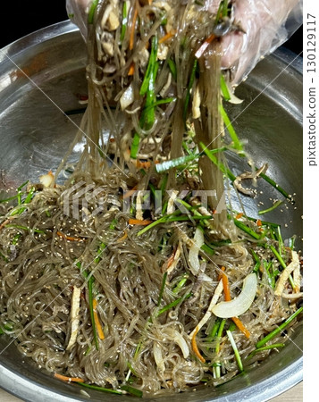 A vibrant plate of japchae featuring stir-fried glass noodles, colorful vegetables, and tender slices of meat, all coated in a savory-sweet soy-based sauce. A classic Korean favorite! 130129117
