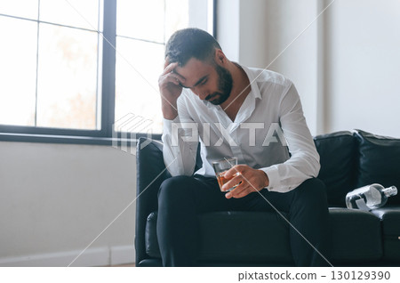 Upset young man drinker alcoholic is indoors Upset young man drinker alcoholic is indoors 130129390