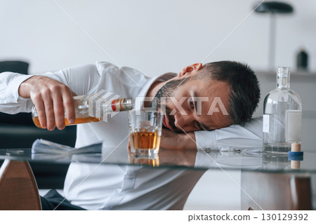 Life crisis. With whiskey. Upset young man drinker alcoholic is indoors 130129392