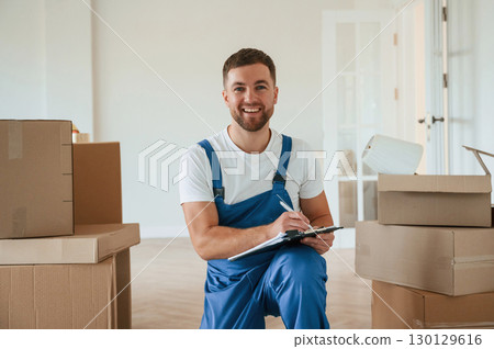 Looking at the camera, holding box. Moving service employee in a room 130129616