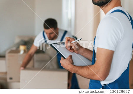 Two moving service employees in a room Two moving service employees in a room 130129637
