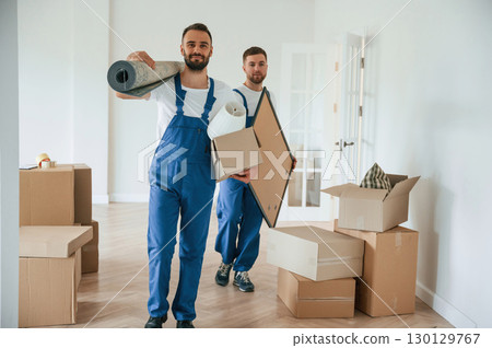 Mat and painting in hands. Two moving service employees in a room 130129767