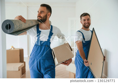 Mat and painting in hands. Two moving service employees in a room 130129771