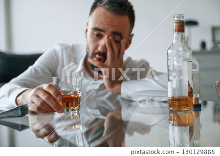Conception of addiction. Upset young man drinker alcoholic is indoors Conception of addiction. Upset young man drinker alcoholic is indoors 130129888