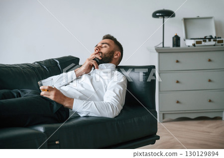 On the black sofa. Upset young man drinker alcoholic is indoors On the black sofa. Upset young man drinker alcoholic is indoors 130129894