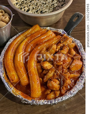 Spicy Korean tteokbokki with chewy rice cakes in a vibrant red sauce, topped with sesame seeds and green onions. A popular street food known for its addictive flavor and satisfying texture. Spicy Korean tteokbokki with chewy rice cakes in a vibrant red sauce, topped with sesame seeds and green onions. A popular street food known for its addictive flavor and satisfying texture. 130129948