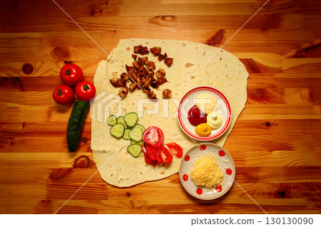 top view of a homemade shawarma on a wooden table, with a focus on fresh ingredients like meat, tomato, and cucumber. top view homemade shawarma recipe. street food photography wooden table 130130090