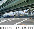 前景是行人穿越道和停車線，頭頂上有高速公路高架橋，背景是建築工地的重型機械和高壓線，路邊散落著垃圾。 130130144