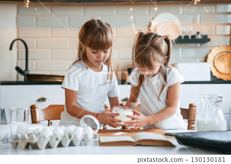Garlands behind. Two little girls are preparing food on the kitchen 130130181