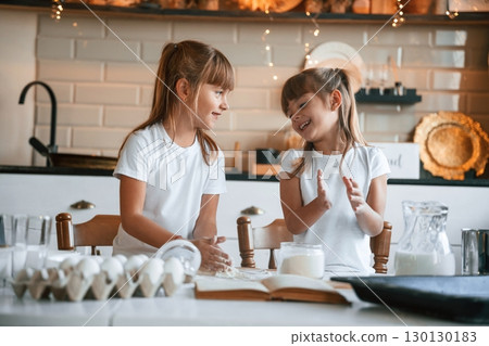 Garlands behind. Two little girls are preparing food on the kitchen 130130183