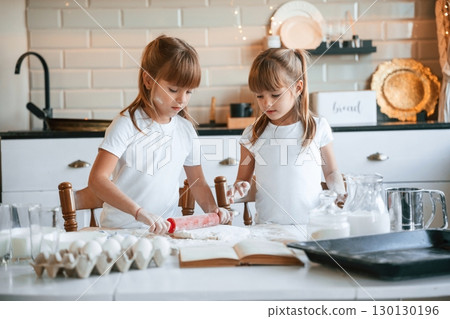 Christmas time. Two little girls are preparing food on the kitchen with garlands Christmas time. Two little girls are preparing food on the kitchen with garlands 130130196