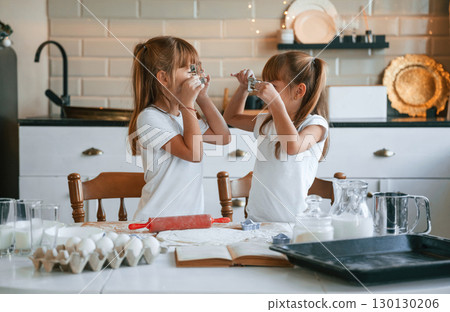 Smiling, playful mood. Two little girls are preparing food on the kitchen with garlands Smiling, playful mood. Two little girls are preparing food on the kitchen with garlands 130130206