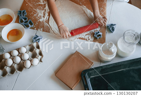 Close up top view of kid's hands that knead the dough on the table with eggs Close up top view of kid's hands that knead the dough on the table with eggs 130130207