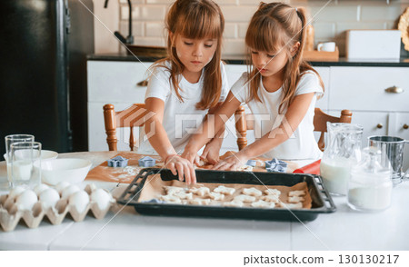 Raw sweet cookies. Two little girls are preparing food on the kitchen with garlands 130130217